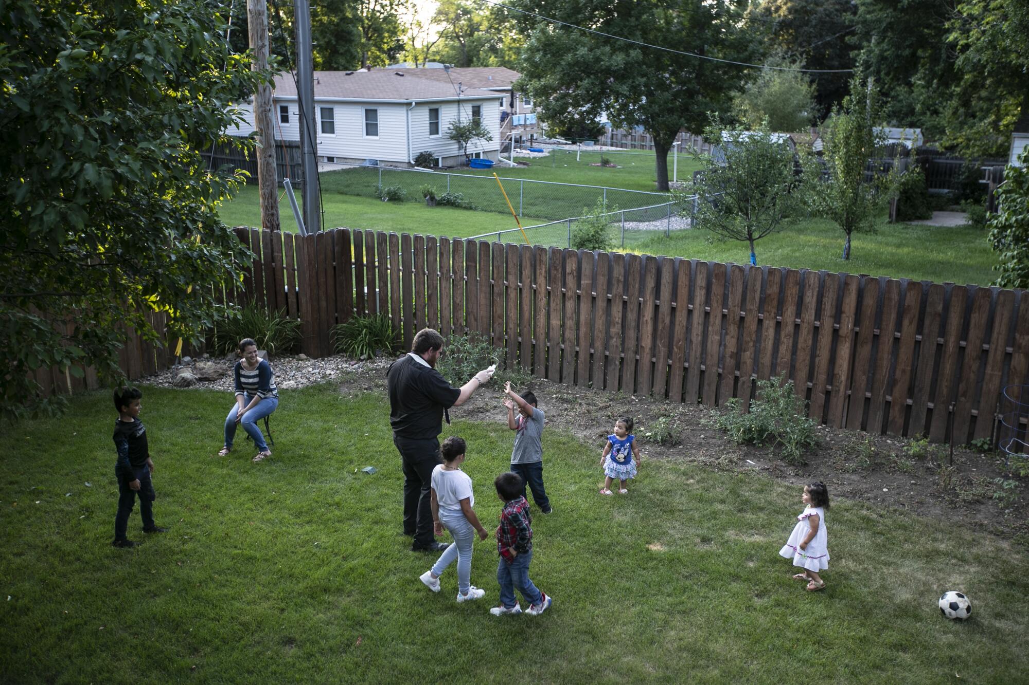 The Rev. Kristopher Cowles slings holy water while blessing the children and the backyard of the Barrera family home.