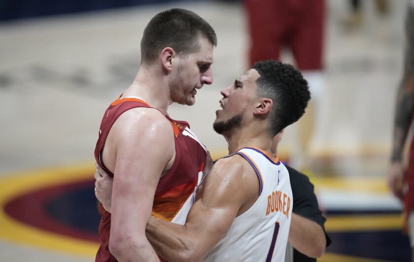 Denver Nuggets center Nikola Jokic, left, squares off against Phoenix Suns guard Devin Booker in the second half of Game 4 of an NBA second-round playoff series Sunday, June 13, 2021, in Denver. (AP Photo/David Zalubowski)