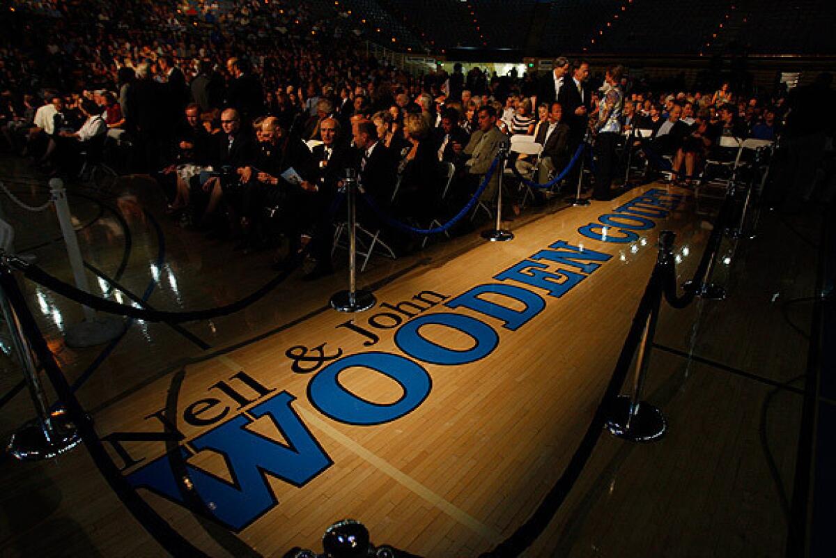 A spotlight shines on the new name for the Pauley Pavilion basketball court at UCLA during the memorial service for the legendary coach.