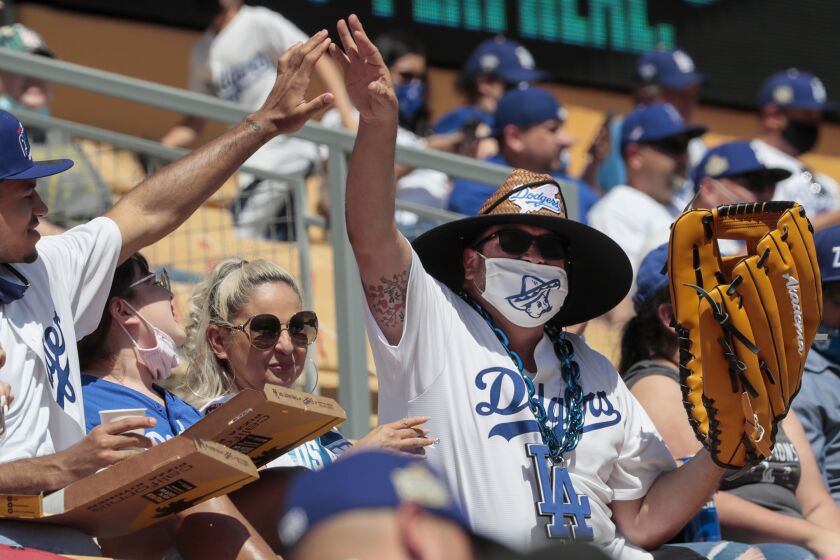 Los Angeles, CA, Friday, April 9, 2021 - A fan with an extra large glove is congratulated after catching a ball in the left field pavilion at Dodger Stadium. (Robert Gauthier/Los Angeles Times)