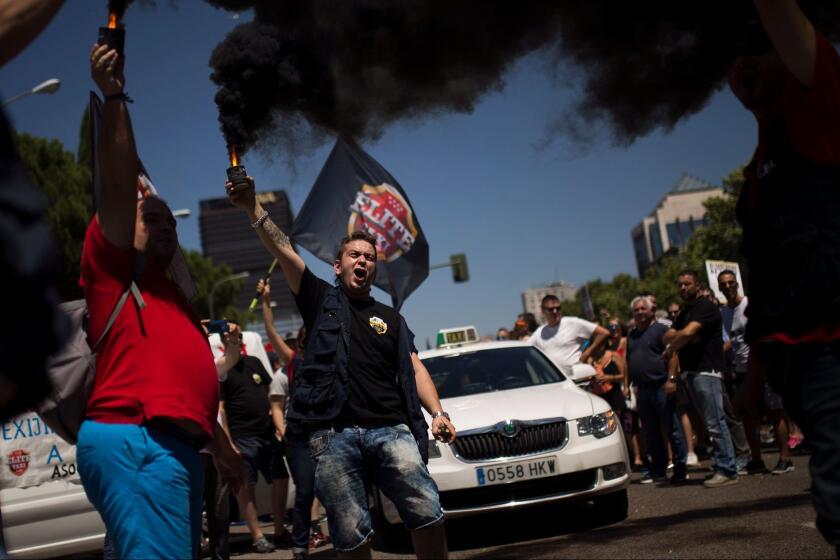 FILE - In this July 27, 2017 file photo, people hold smake flares and shout slogans during a protest by Spanish taxi drivers unions against companies such as Uber and Cabify in Madrid, Spain. The European Union's top court has ruled on Wednesday Dec. 20, 2017 that ride-hailing service Uber should be regulated like a taxi company, a decision that could change the way it functions across the continent. (AP Photo/Francisco Seco, File)