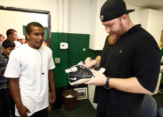 Sam Baker, a three-time All-American tackle at USC and a current starting left tackle for the Atlanta Falcons, signs a shoe for Oronde Crenshaw at Costa Mesa High School on Wednesday.
