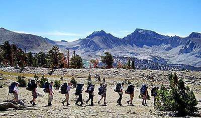 The crew hikes along the Bighorn Plateau portion of the John Muir Trail. The peaks of Mt. Whitney are in the background.