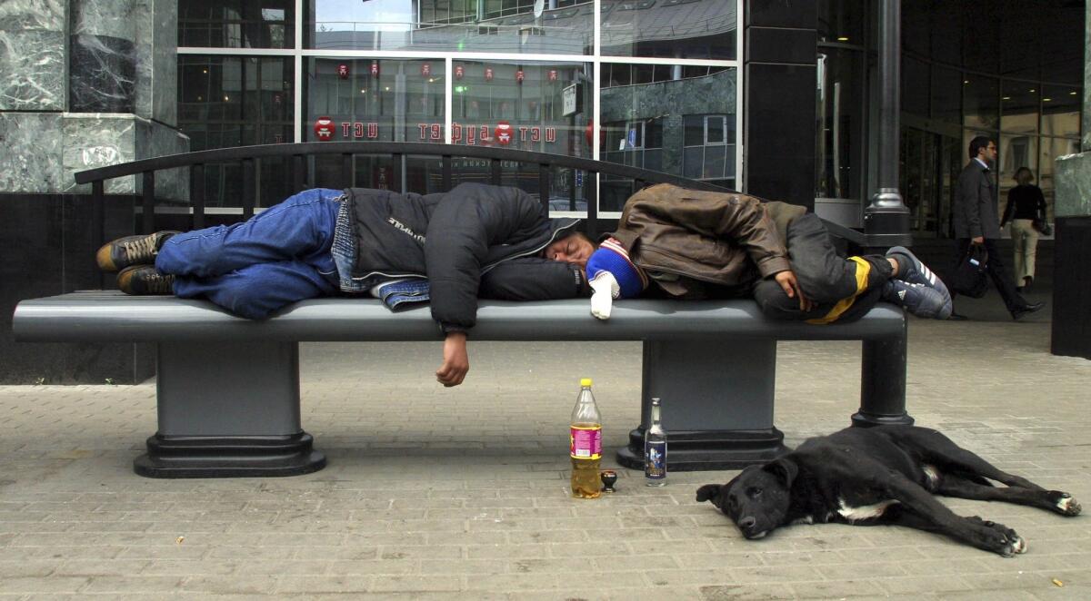 Before laws banned public consumption of alcohol, two men sleep with bottles of alcohol at hand on a Moscow street in 2005.