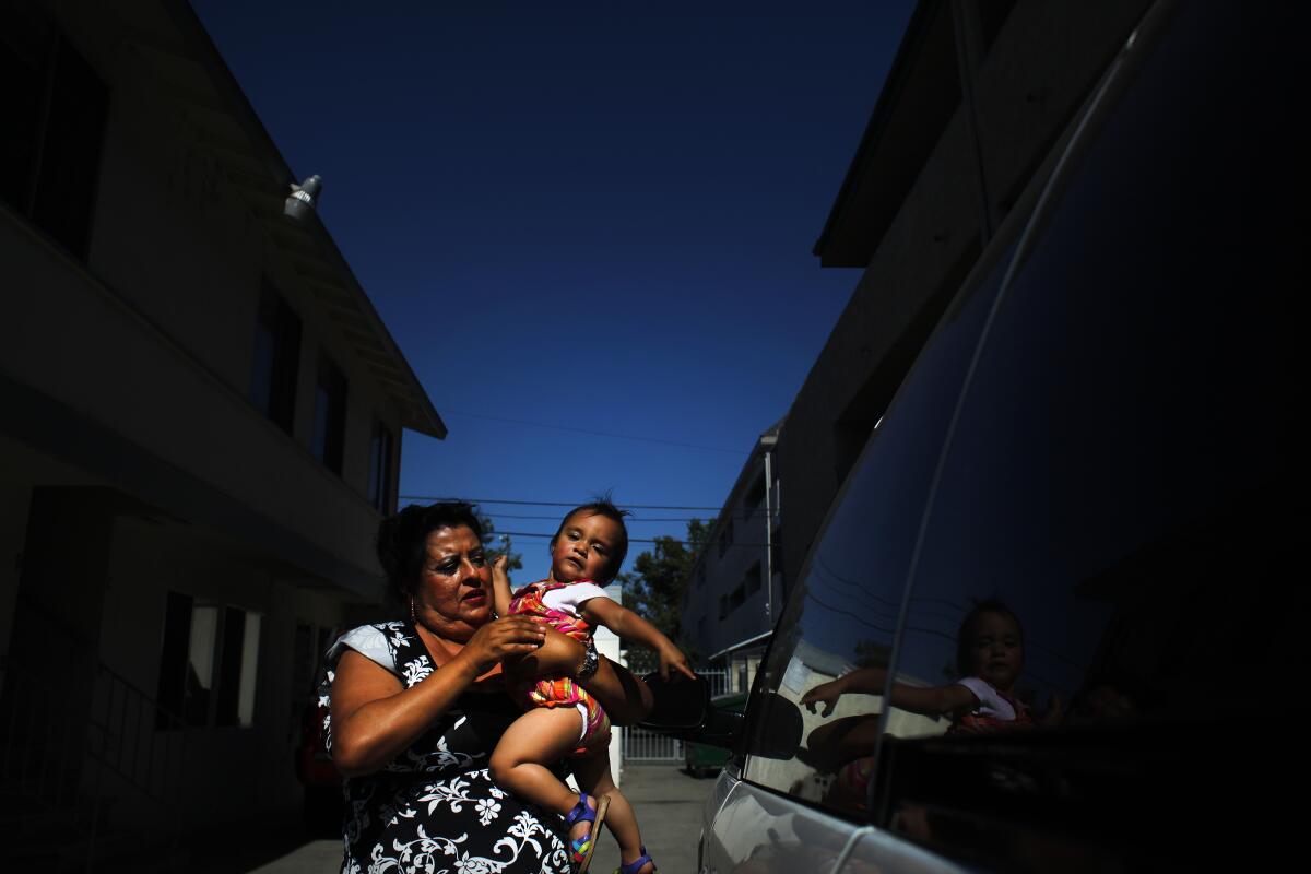 A mother and her child stand outside their apartment in Santa Ana.