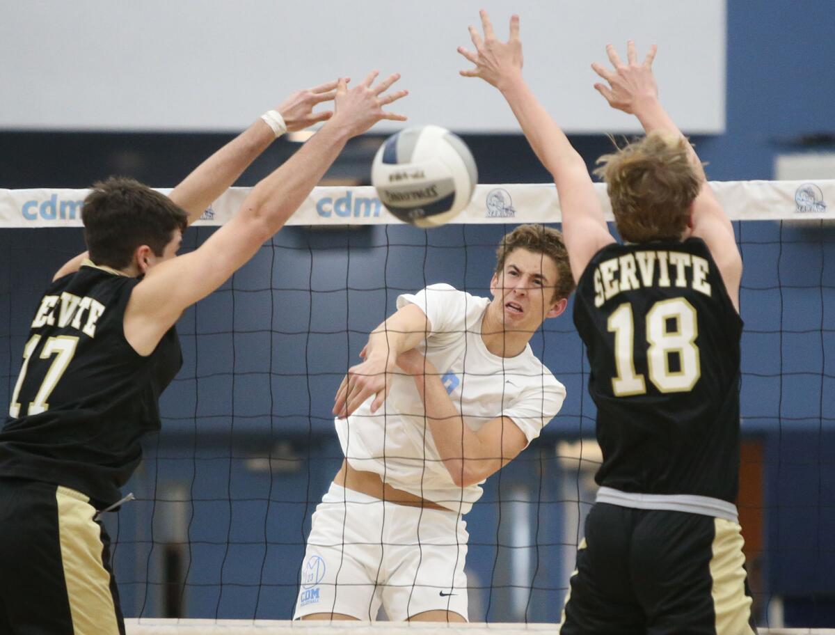 Corona del Mar's Nato Dickinson puts away a kill between Servite's Max Colgan (17) and Peter Selcho (18) during a nonleague match on Tuesday.
