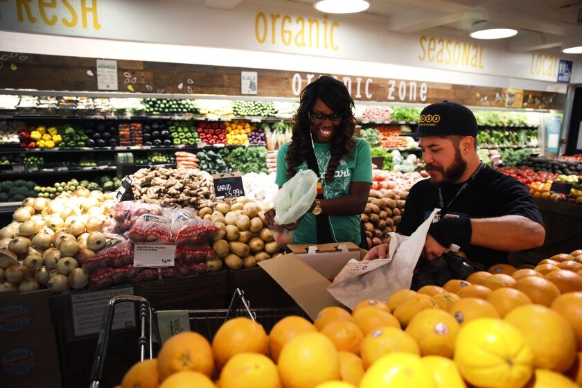 SHERMAN OAKS, CA, FRIDAY, SEPTEMBER 12, 2014 - Whole Foods team member Matthew Otsuka opens a box of peaches for Instacart shopper Kara Pete as she shops for Concologist Tricia Carr. (Robert Gauthier/Los Angeles Times)