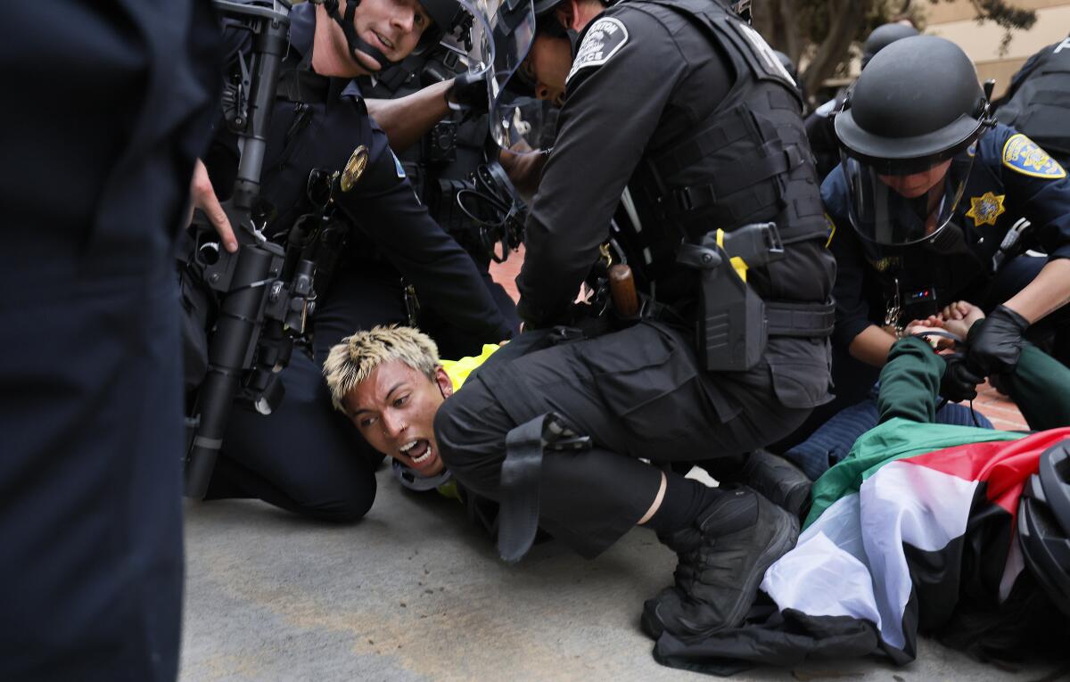  Two demonstrators are on the ground as they are taken into custody by police.  