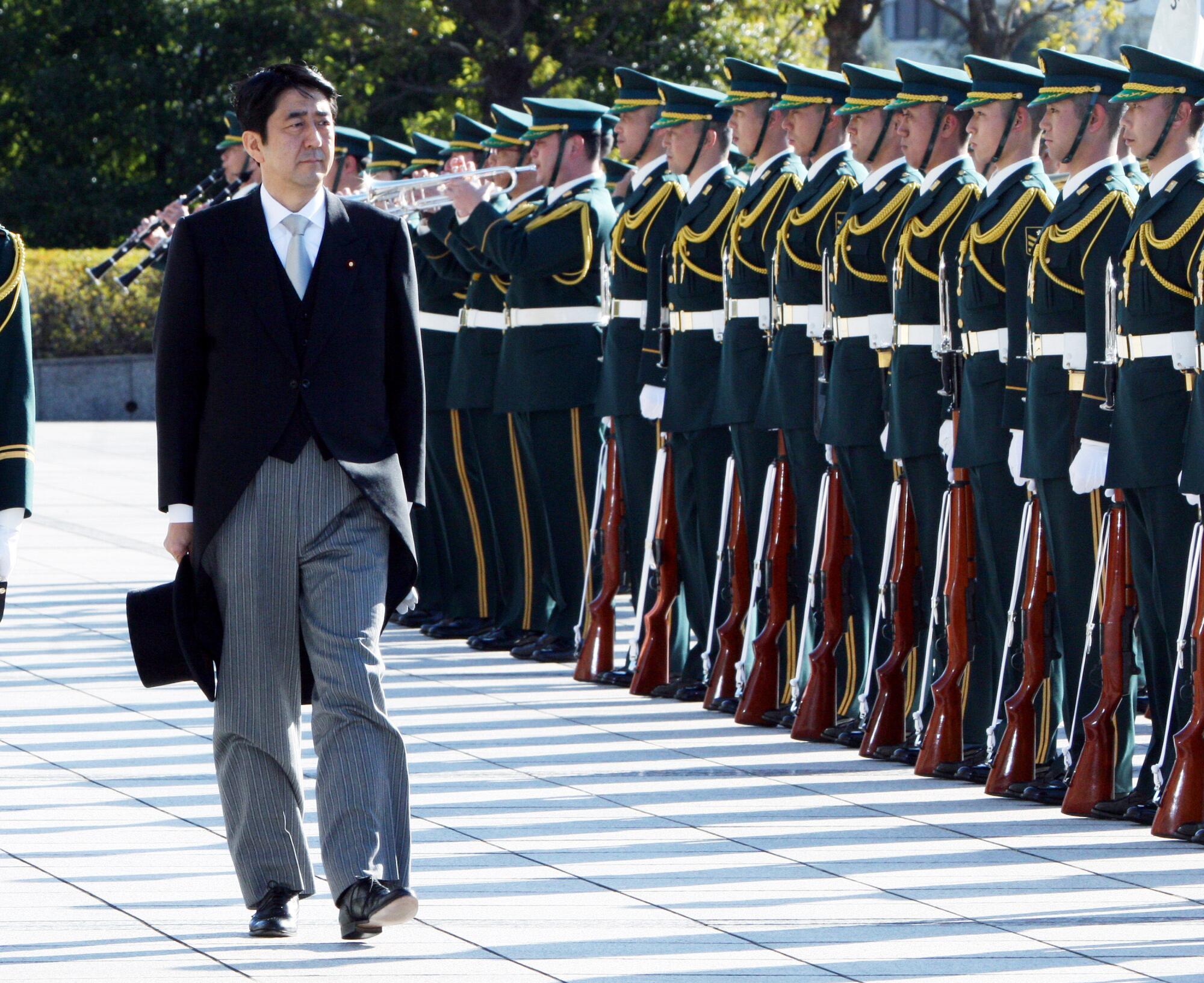 Shinzo Abe, Japan's prime minister, reviews the honor guard at a ceremony for the Ministry of Defense 