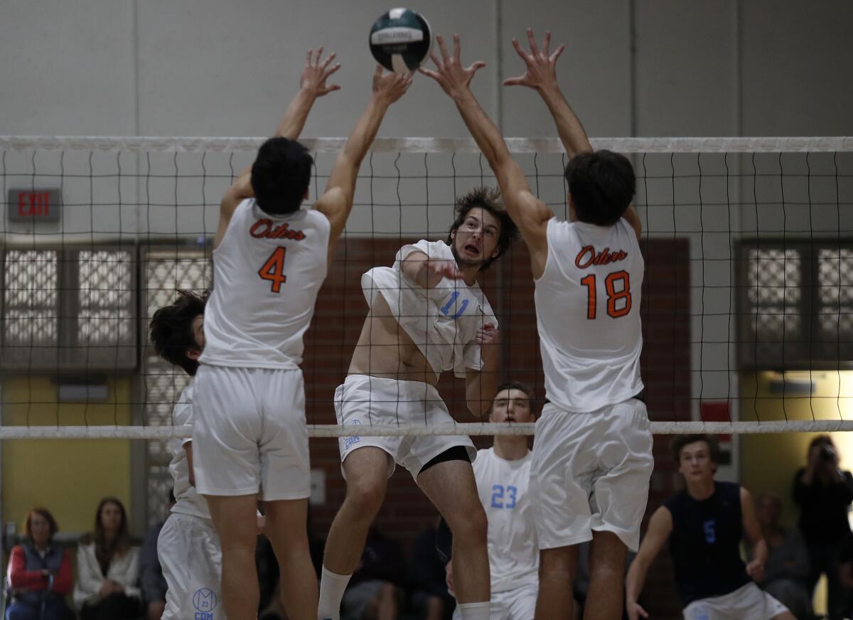 Corona del Mar's Glen Linden (11) hits against Huntington Beach's Sinjin Choi (4) and Drake Goering (18) in the first set of an Orange County Championships boys' volleyball tournament semifinal match at Edison High on Saturday.