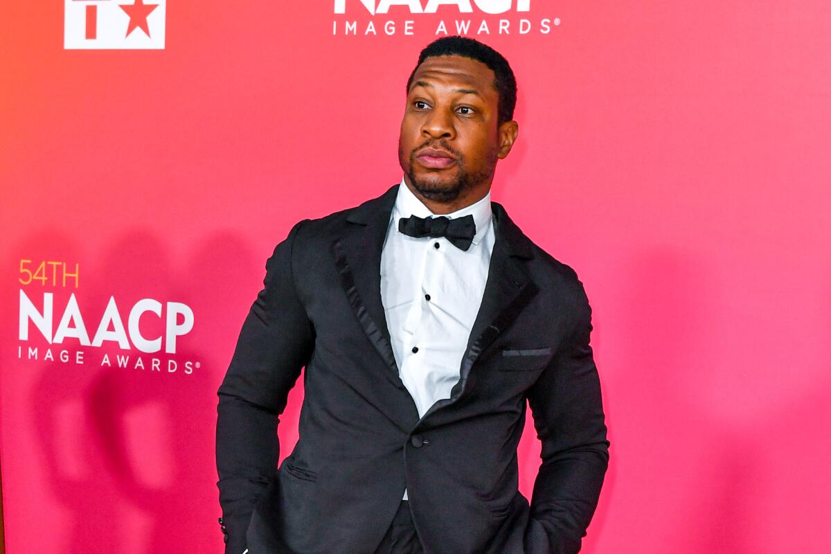 Jonathan Majors stands with his hands in his tuxedo's pants pockets