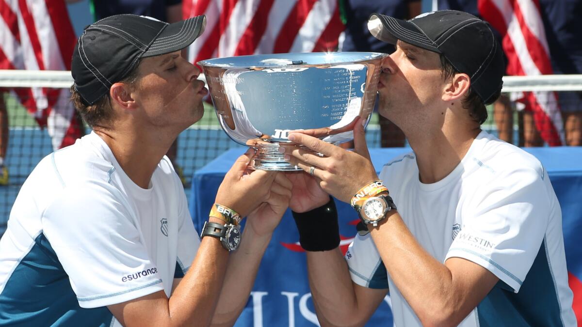 Bob, left, and Mike Bryan kiss the men's doubles championship trophy after defeating Marc Lopez and Marcel Granollers at the U.S. Open on Sunday.
