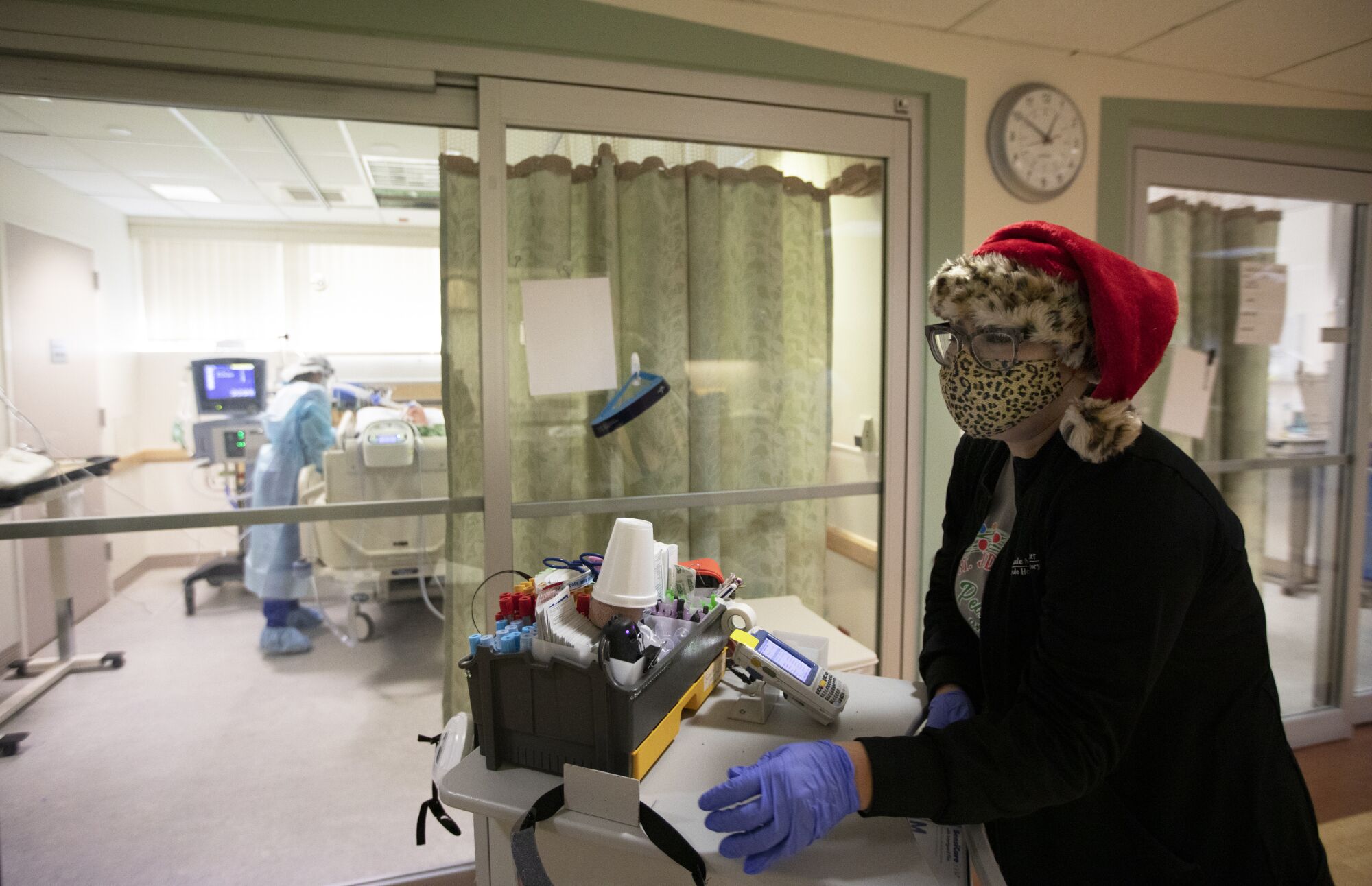 Brenda Lorenzo wears a Santa hat and a leopard mask over her N95 in the ICU 