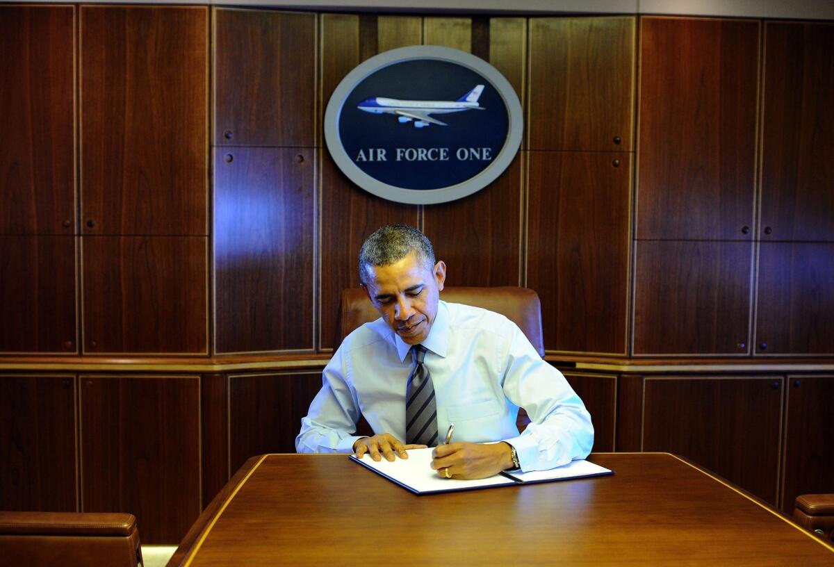 Traveling aboard Air Force One, President Obama signs an executive order on streamlining the nation's export-import process.