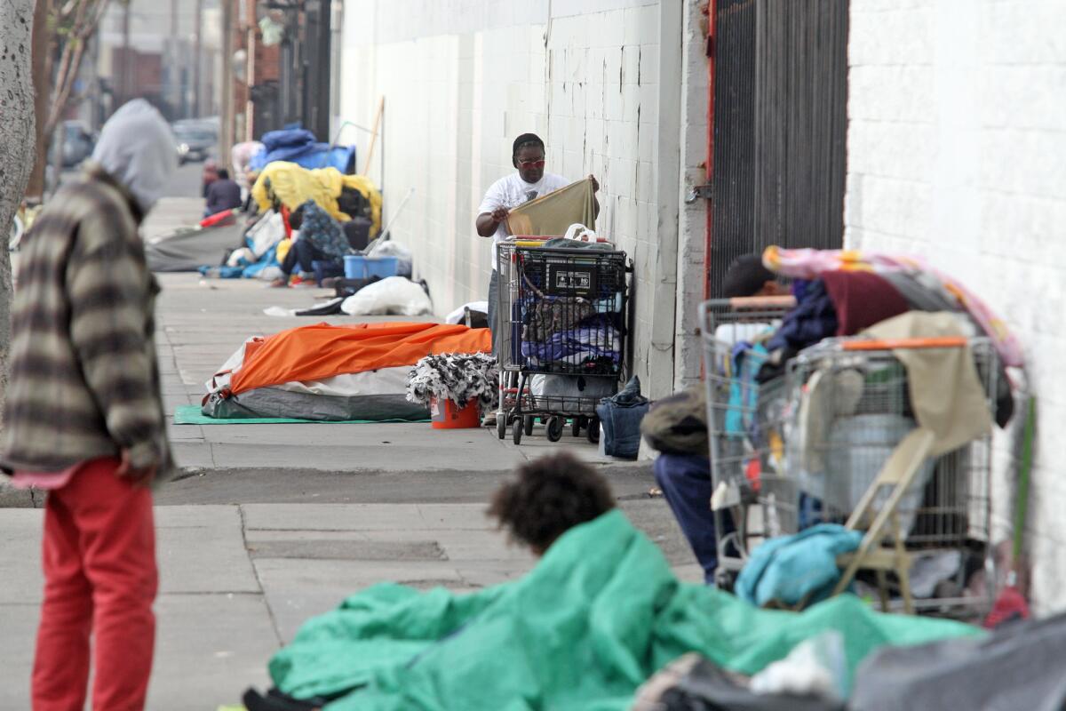 Annie Moody adjusts belongings next to her tent on Towne Avenue at 6th Street in Los Angeles.