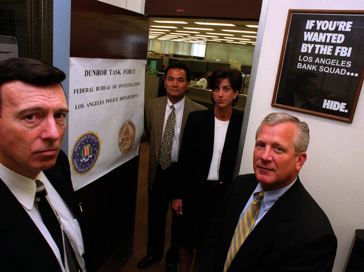 Four law enforcement officials stand next to FBI posters