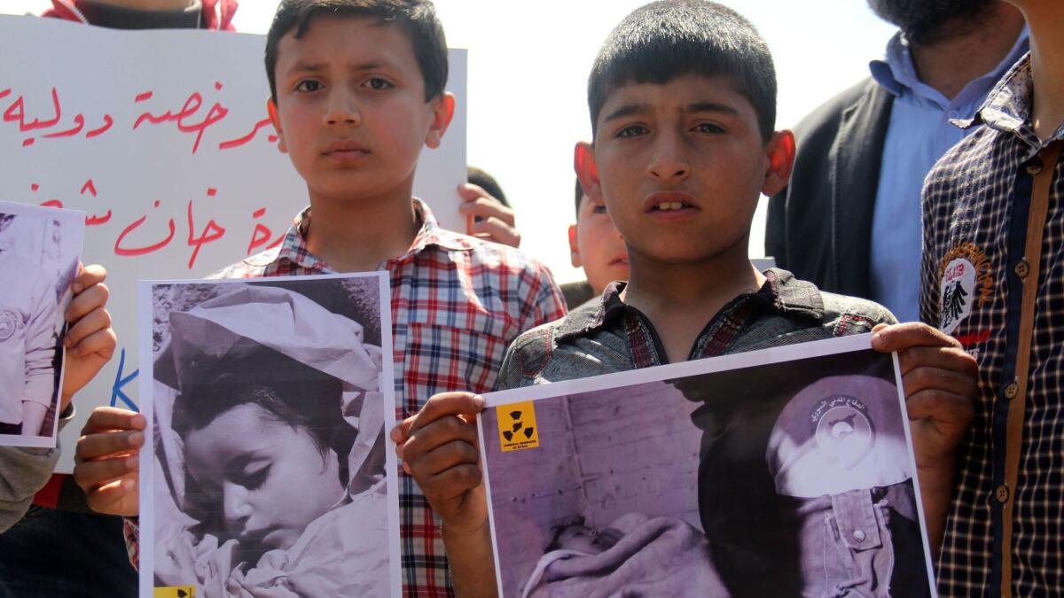 In this photo taken on April 7, Syrian residents of Khan Sheikhun hold up placards and photographs during a protest condemning a suspected chemical weapons attack on their town that killed at least 86, including 30 children.