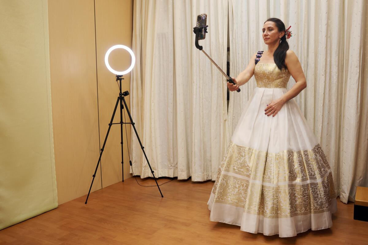 A woman takes a selfie wearing a dress in a clothing store