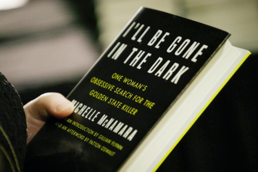 A hand holding a copy of Michelle McNamara's book "I’ll Be Gone In The Dark"