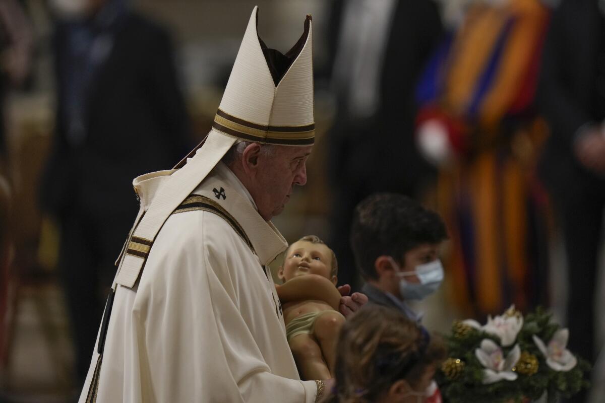 Pope Francis carries a statuette of Baby Jesus as he celebrates Christmas Eve Mass at St. Peter's Basilica 