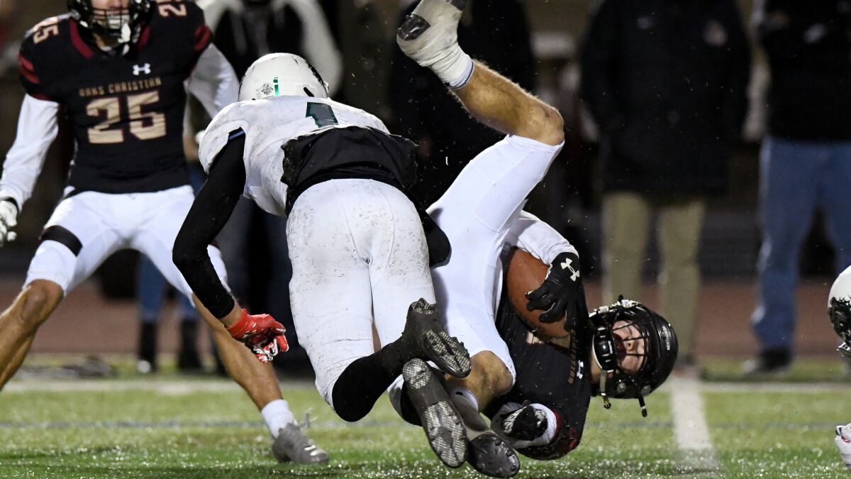 Oaks Christian's Robert Fletcher is upended by Helix's Jayden Tauanuu after a reception during the Division 1-AA state playoff game on Friday night.
