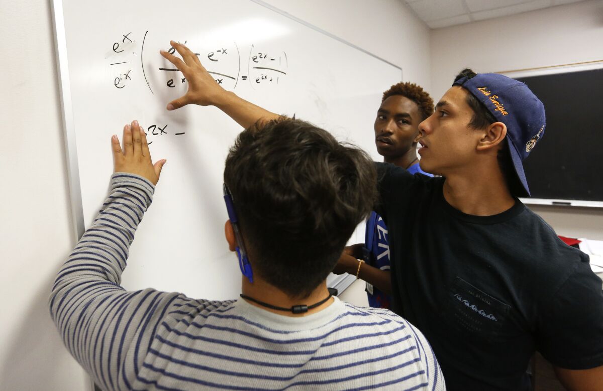 Teacher's assistant Alejandro Fernandez, right, helps Carlos Rivas, 17, left, and David-Earl Russell, 17, with a precalculus equation as part of the college-prep South Central Scholars Summer Academy at USC.