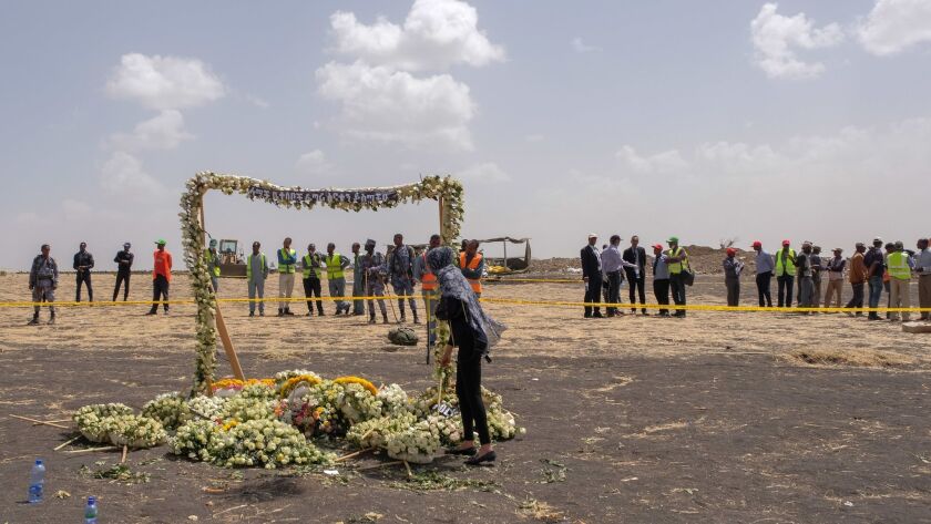 A mourner lays flowers at a memorial arch at the crash site of Ethiopian Airlines Flight 302 on Thursday in Ejere, Ethiopia.