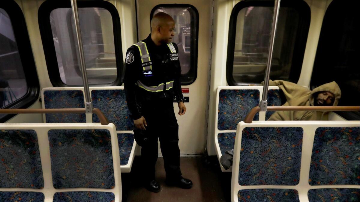 Metro transit security guard Tracey Houston rouses a man sleeping on the Metro Red Line subway. Early-morning and late-night trains are often a refuge for homeless people looking for a warm place to sit or sleep.