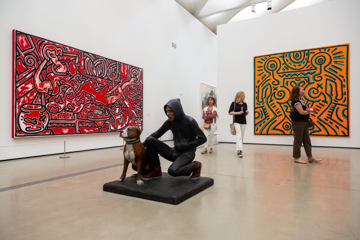 LOS ANGELES, CALIF. - APRIL 23: People walk through the gallery, in view of Keith Hering's "Red Room," on the left, and "Untitled," on the right, and John Ahearn's "Raymond and Toby," in the center, photographed on Tuesday, April 23, 2019 in Los Angeles, Calif. (Kent Nishimura / Los Angeles Times)