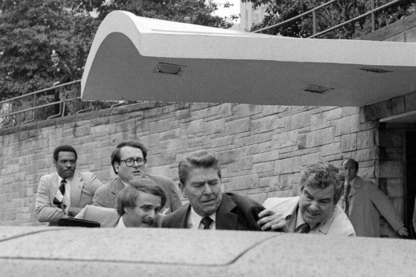 ARCHIVO - El presidente Ronald Reagan es empujado hacia su limusina por agentes del Servicio Secreto tras ser baleado el 30 de marzo de 1981, afuera de un hotel de Washington. (AP Foto/Ron Edmonds, archivo)