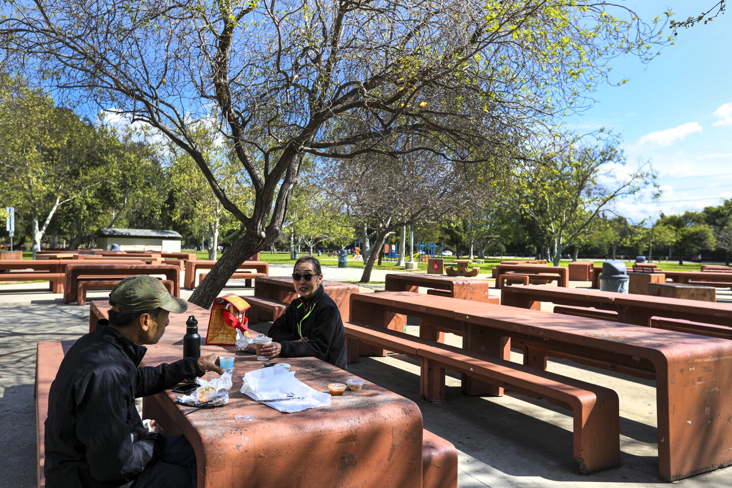 LOS ANGELES, CA - MARCH 28, 2020 - Mong Noiboonsok, left, and Rena Chastan, after a morning run have lunch on a sunny Saturday March 28, 2020, at Crystal Springs Picnic area in Griffith Park. As Los Angeles County has closed all of its beaches in an effort to reduce crowds as officials try to enforce social-distancing guidelines to slow the spread of coronavirus many went to parks. (Irfan Khan / Los Angeles Times)