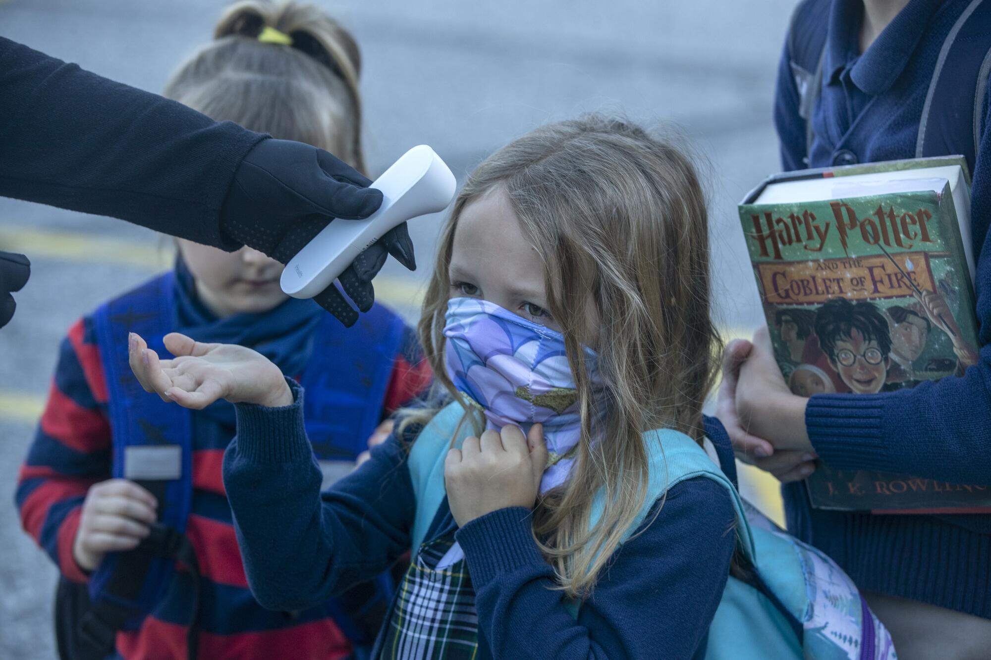 A kindergartener's temperature is taken outside the school.