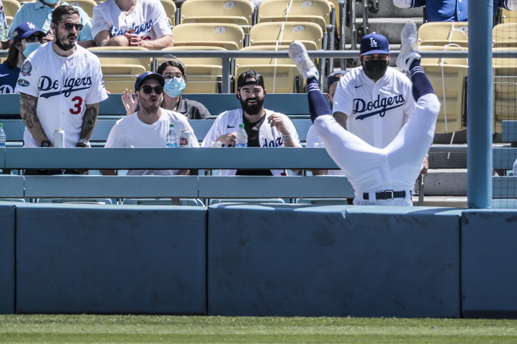 Los Angeles Dodgers right fielder Zach McKinstry (8) tumbles over the wall after missing a second-inning foul ball.