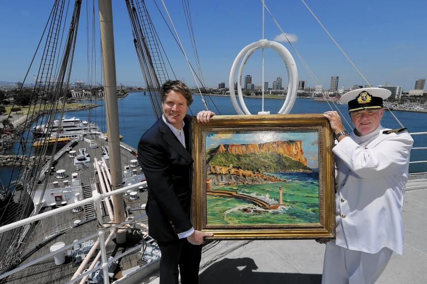 Duncan Sandys, left, great grandson of Sir Winston Churchill, and Commodore Everett Hoard hold up a painting done by Sir Winston Churchill titled "Coast Scene Near Marseilles" from the 1930s, an oil on canvas. It will be on exhibit at an art gallery aboard the Queen Mary in Long Beach from May 27 to Dec. 31, 2016.