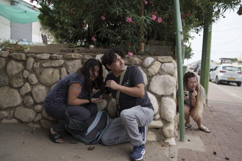 FILE - Israelis take cover from the incoming rocket fire from the Gaza Strip in Ashkelon, southern Israel on Oct. 11, 2023. (AP Photo/Leo Correa, File)