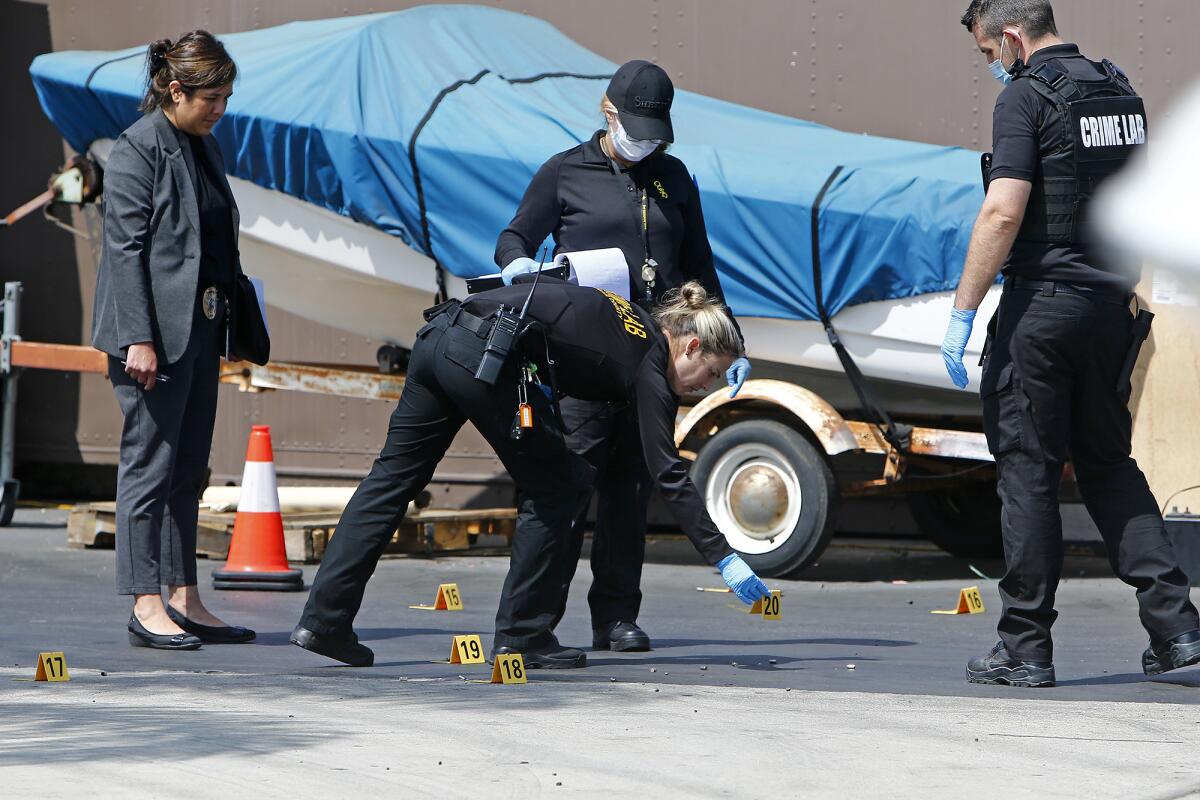 O.C. Crime Lab investigators Wednesday examine bullet casings outside Advanced Marine Services in Costa Mesa.