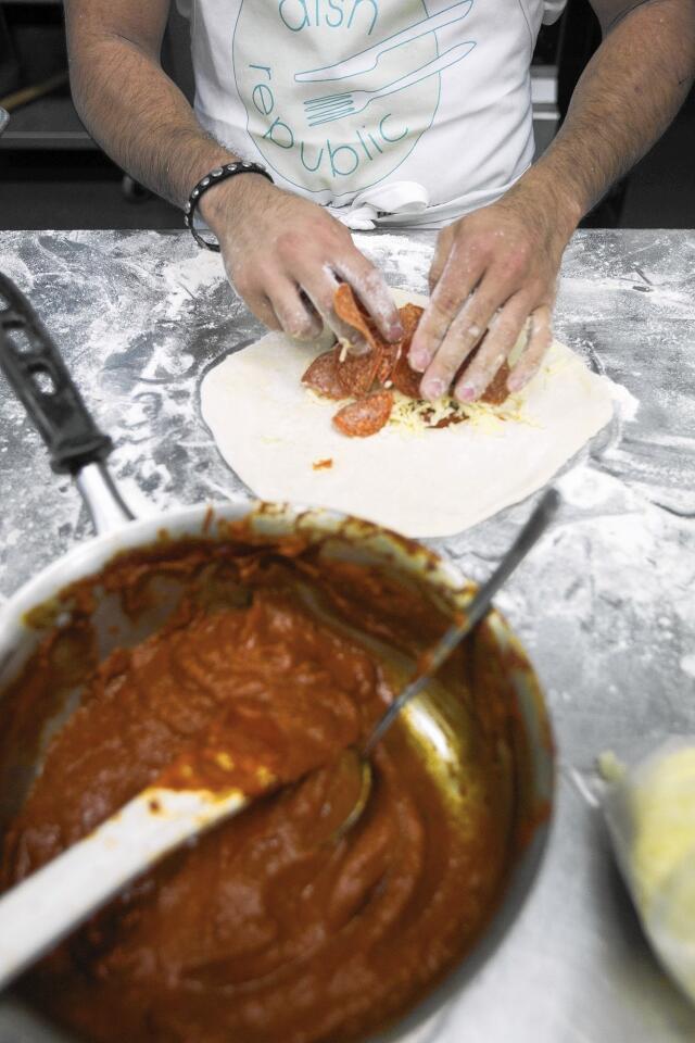 Chef Aldrich Mendiola prepares a pizza pocket for Dish Republic, a food delivery service based at The Hood commercial kitchen in Costa Mesa.