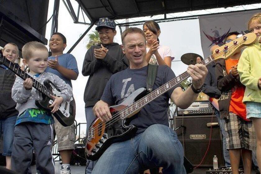 Gary Sinise with his Lt. Dan Band shows off his bass playing to Andrew James Bretzman, 3, after inviting children onto the stage.