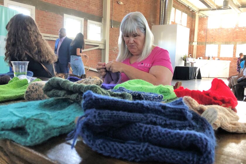 Marianne Mesa of Point Loma knits a hat at the Oct. 3 kickoff party Oct. 3 at Liberty Station, for the Gifted Back website 