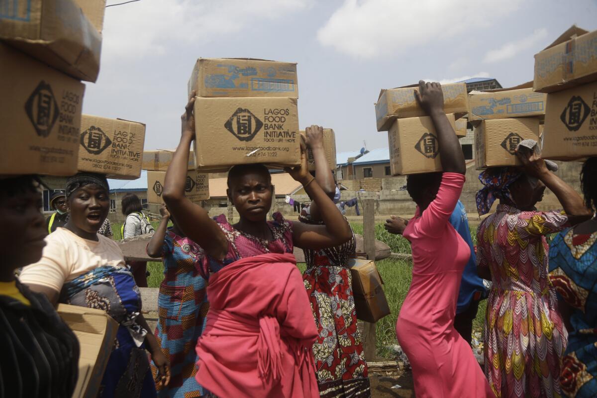 Residents of Oworonshoki Slum carry their food parcels distributed by the Lagos Food Bank Initiative, a non-profit nutrition focused initiative committed to fighting hunger and solving problems of Malnutrition for poor communities , in Lagos, Nigeria, Saturday, July 10, 2021. (AP Photo/Sunday Alamba)