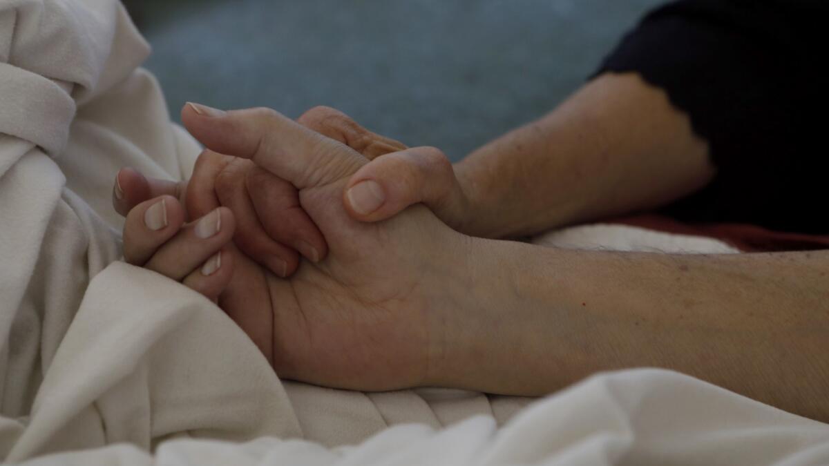A woman holds the hand of her husband, who is in hospice care. More Americans are opting to spend their final days outside of a hospital setting, according to a new study.