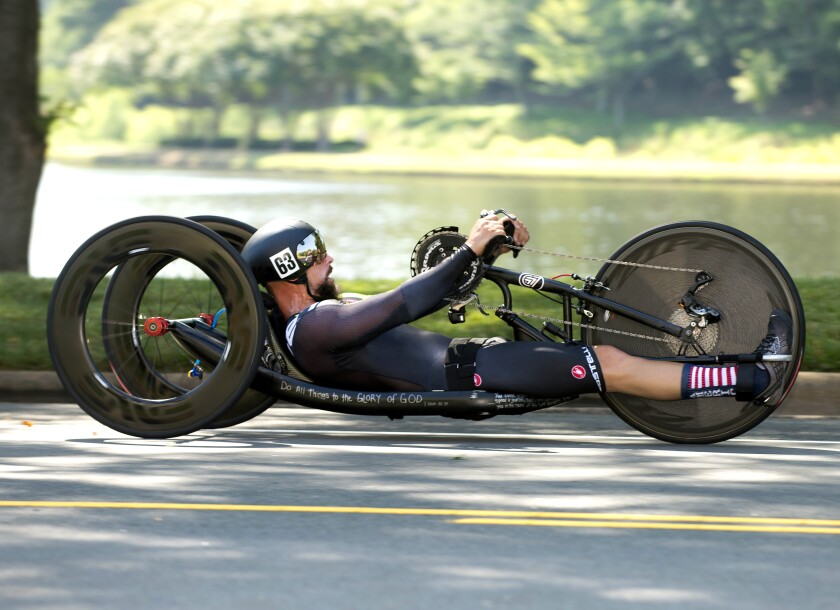 A male athlete races a recumbent hand-bike. 