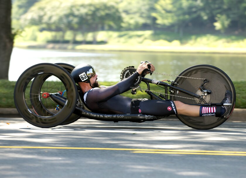 A male athlete races a recumbent hand-bike.