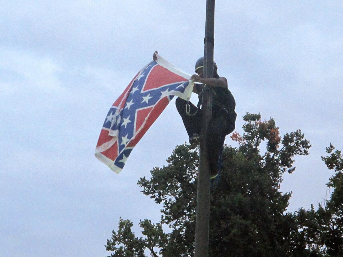 Bree Newsome, de Charlotte, Carolina del Norte, muestra la bandera Confederada luego de retirarla de lo alto de un asta de un monumento al bando Confederado de la Guerra Civil en los terrenos del capitolio estatal en Columbia, Carolina del Sur, el sábado 27 de junio de 2015. (Foto AP/Bruce Smith)