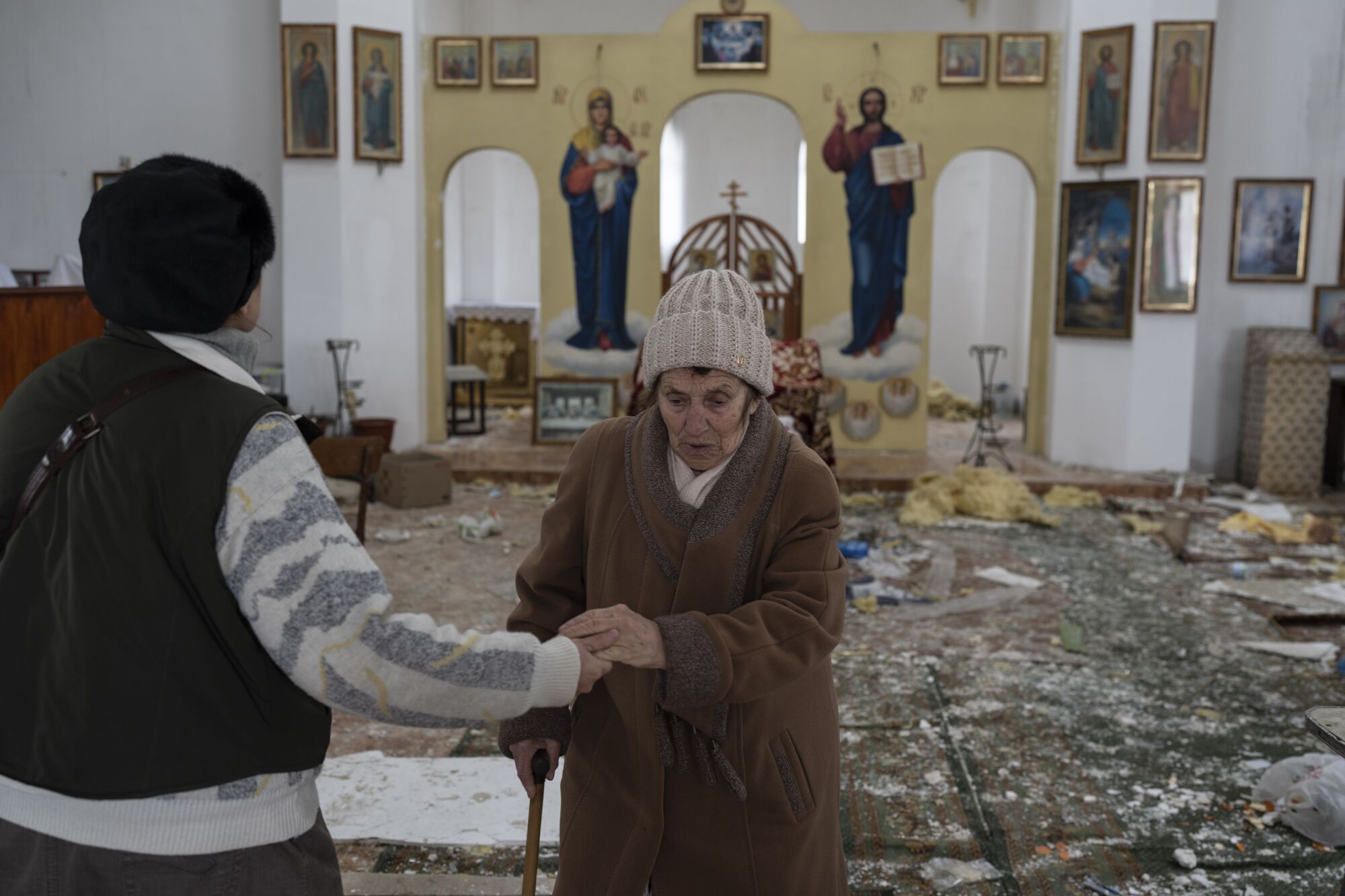 A woman reacts as she enters a war-damaged church.