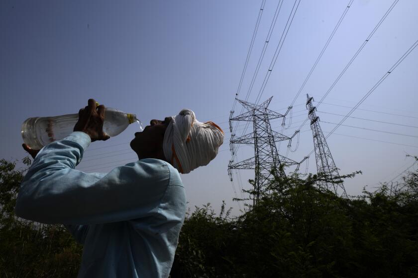 A workers quenches his thirst next to power lines as a heatwave continues to lashes the capital, in New Delhi, India, Monday, May 2, 2022. An unusually early and brutal heat wave is scorching parts of India, where acute power shortages are affecting millions as demand for electricity surges to record levels. (AP Photo/Manish Swarup)