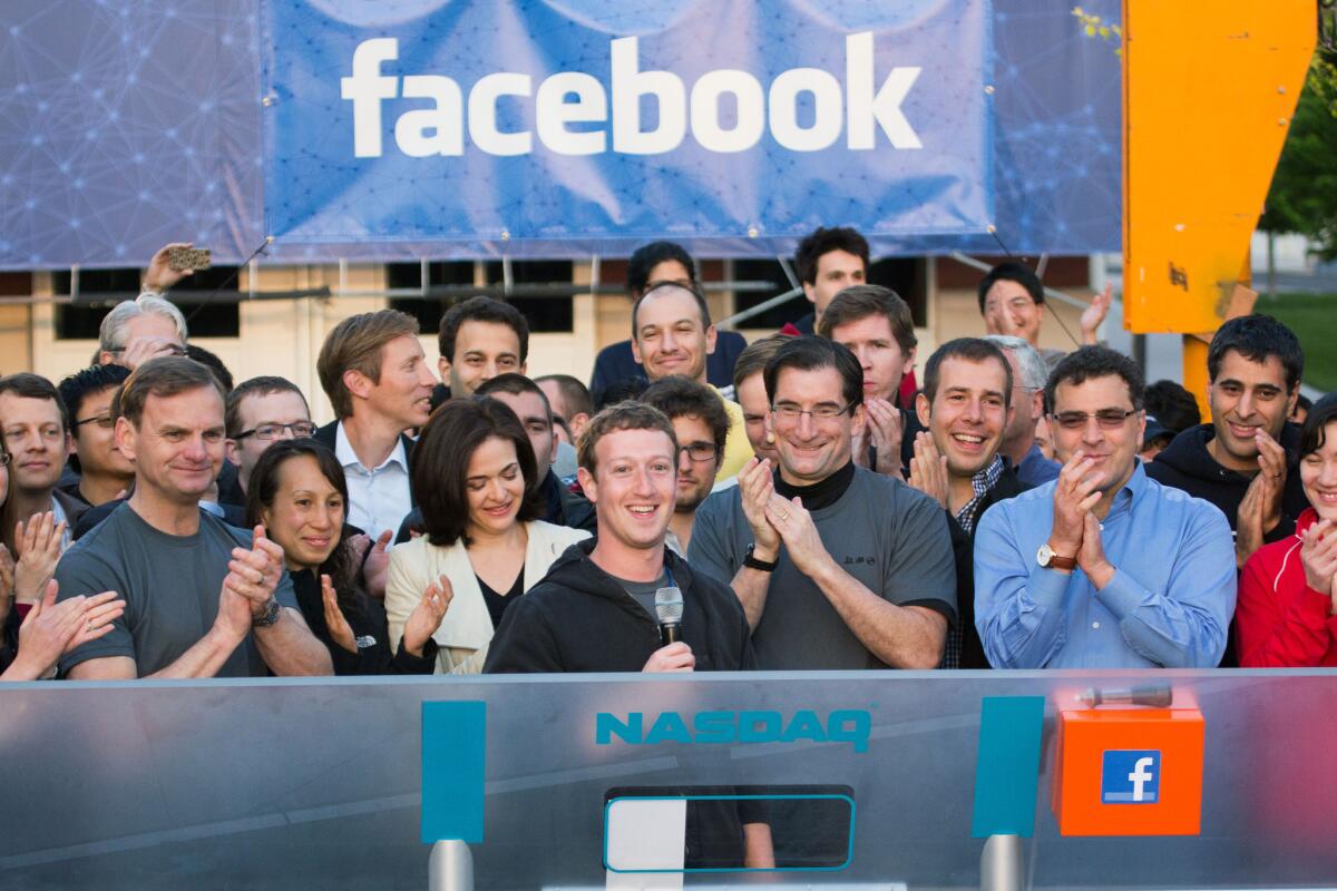 Facebook founder, chairman and CEO Mark Zuckerberg, center, rings the opening bell of the Nasdaq stock market from Facebook headquarters in Menlo Park. Calif., on the day the company went public last year.