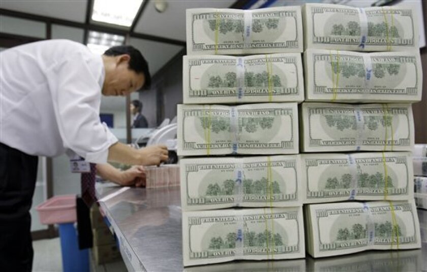 A foreign currency bank clerk works next to bundles of banknotes at the head office of Korea Exchange Bank in downtown Seoul, South Korea, Monday, Nov. 10, 2008. Fitch Ratings on Monday lowered the sovereign credit rating outlooks for six emerging market economies to reflect possible increased burdens stemming from the global credit crisis and slowing economy. (AP Photo/Lee Jin-man)