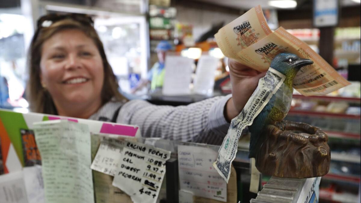 Juana Soto of Inglewood rubs her lottery tickets against a blue bird figure for good luck at the Blue Bird Liquor store in Hawthorne in October, when the Mega Millions jackpot was worth more than $1 billion.