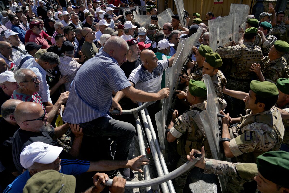 Soldiers scuffle with retired army members as they try to enter to the parliament building while the legislature was in session discussing the 2022 budget, during a protest in downtown Beirut, Lebanon, Monday, Sept. 26, 2022. The protesters demanded an increase in their monthly retirement pay, decimated during the economic meltdown. (AP Photo/Bilal Hussein)
